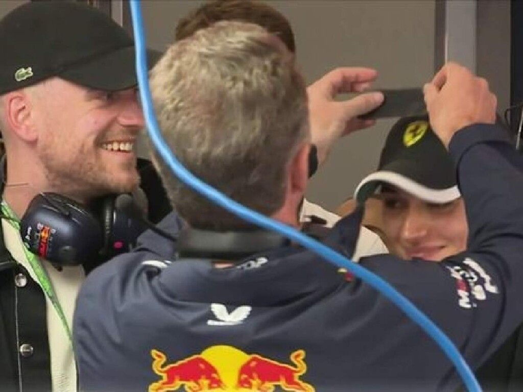 Christian Horner covering a Ferrari logo on a fan's cap