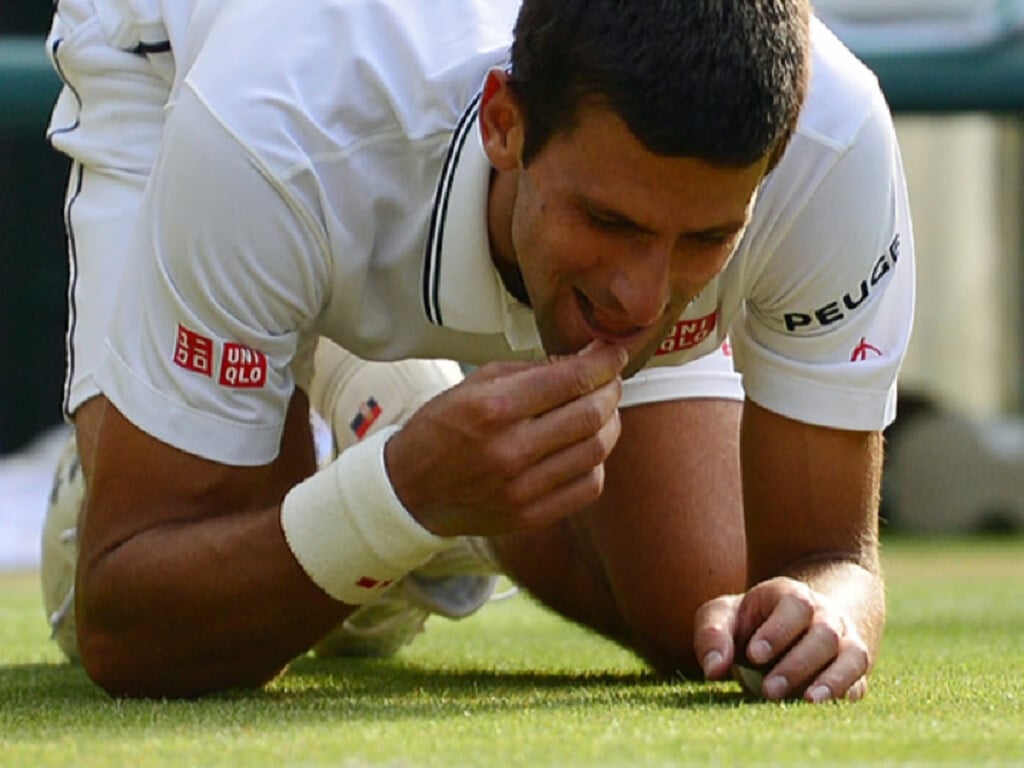 novak djokovic eating wimbledon court grass