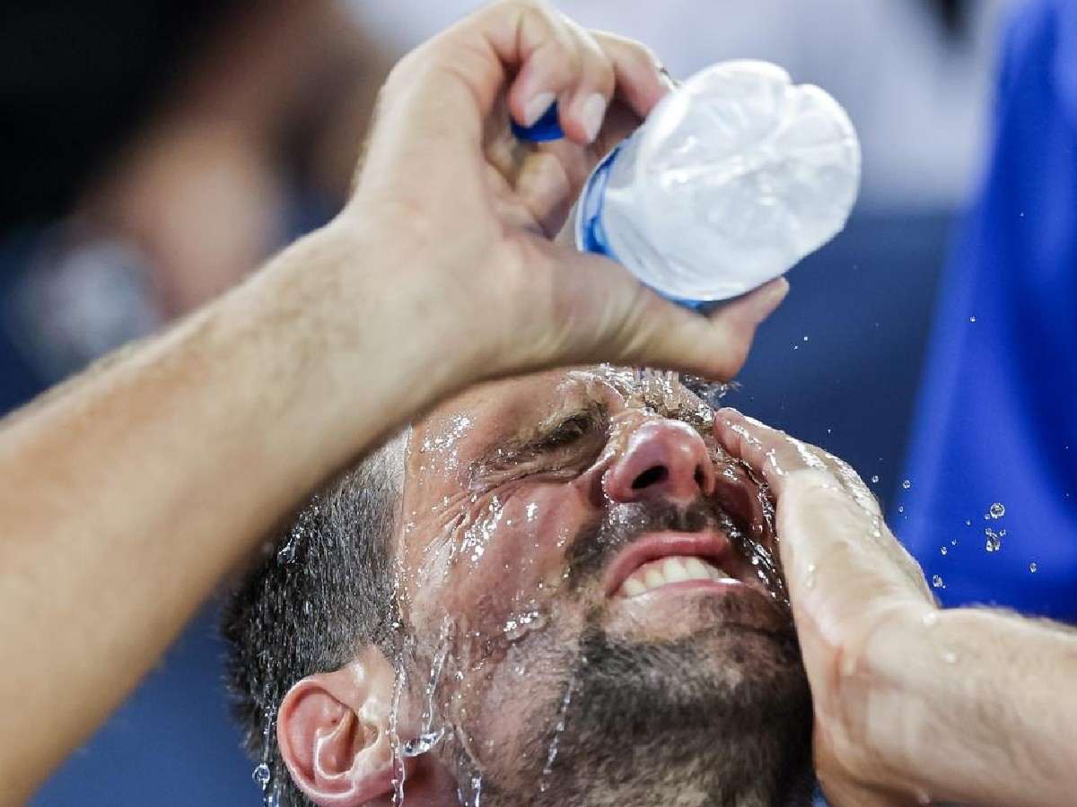 Novak Djokovic drenches himself with water
