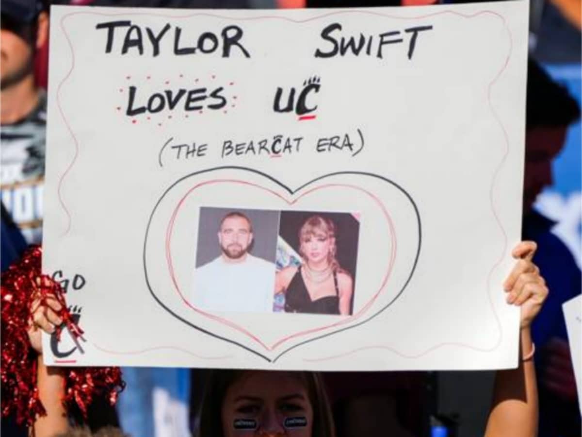 A fan holding a Kelce-Swift play card in the stands