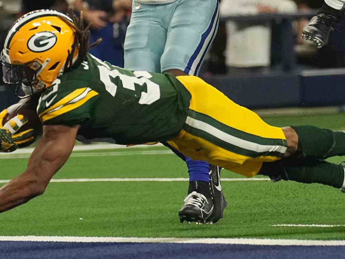 Green Bay Packers running back Aaron Jones (33) scores a touchdown despite the efforts of Dallas Cowboys cornerback DaRon Bland (26) during the third quarter in a 2024 NFC wild card game at AT&T Stadium. 